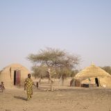 Woodless construction hut next to traditional shelter.